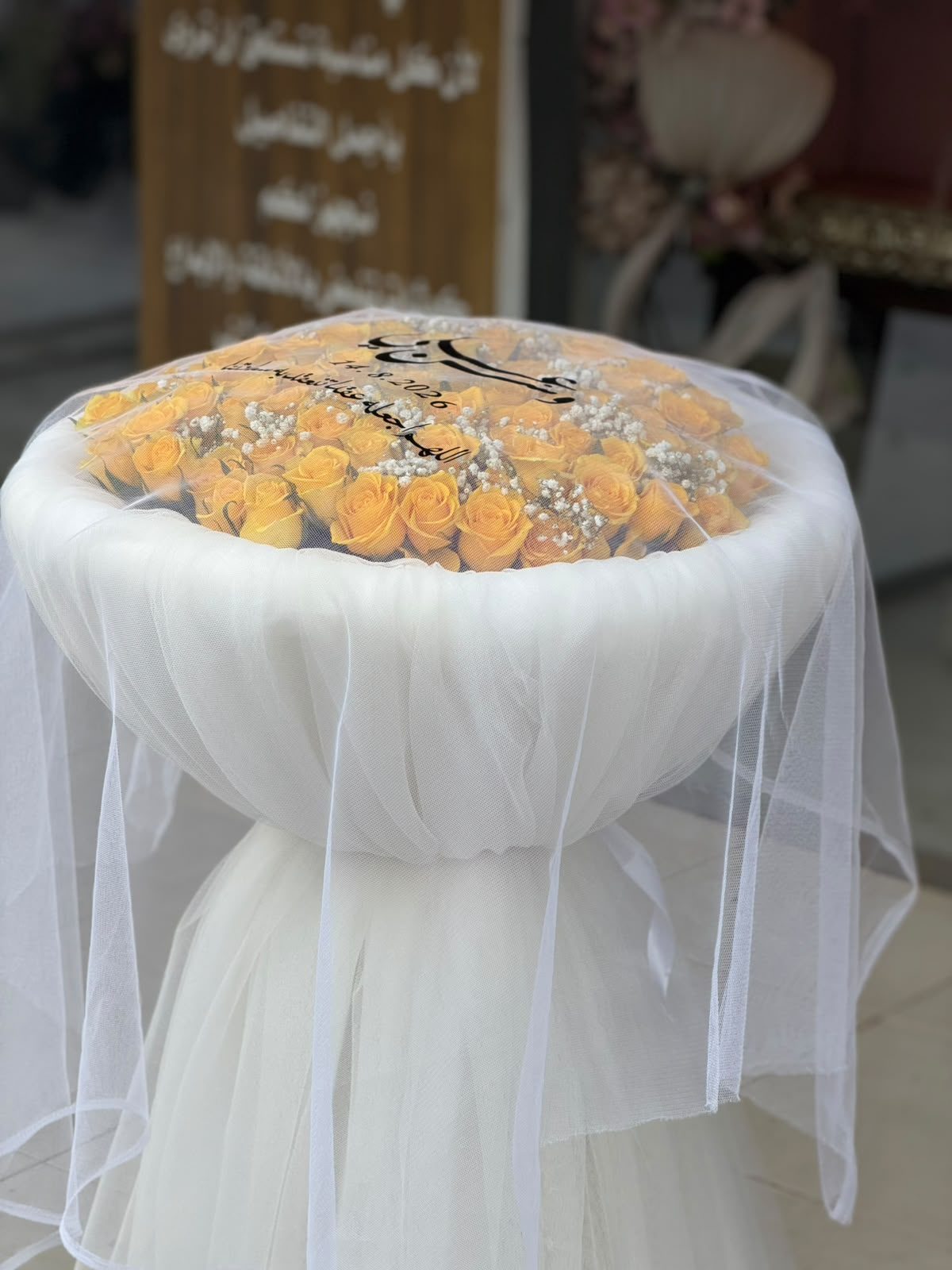 باقة ورد جوري أصفر بتغليف تل أبيض معروضة أمام واجهة المحل